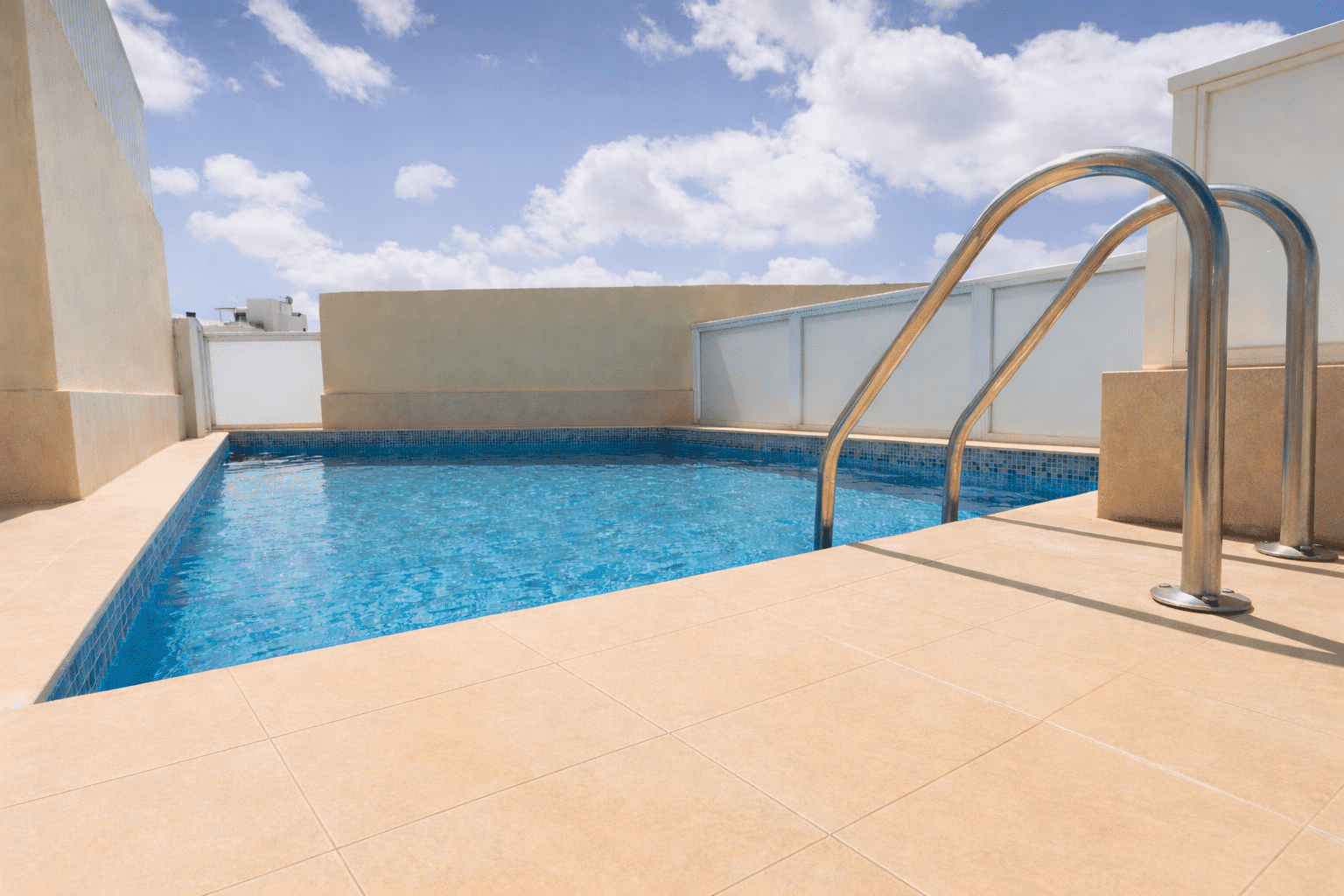 Sunny rooftop pool with clear water.