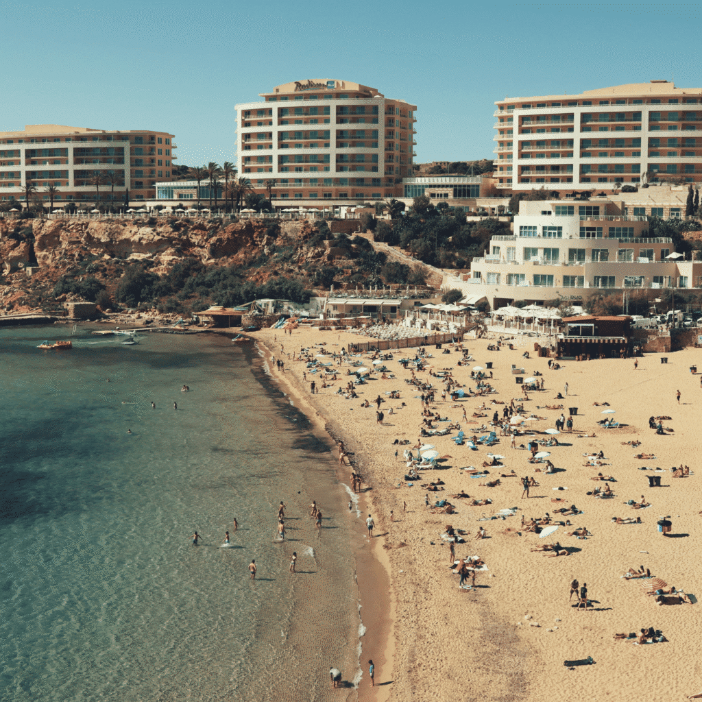 A vibrant scene on Maltas sandy beach with tourists enjoying the sun and the Mediterranean Sea