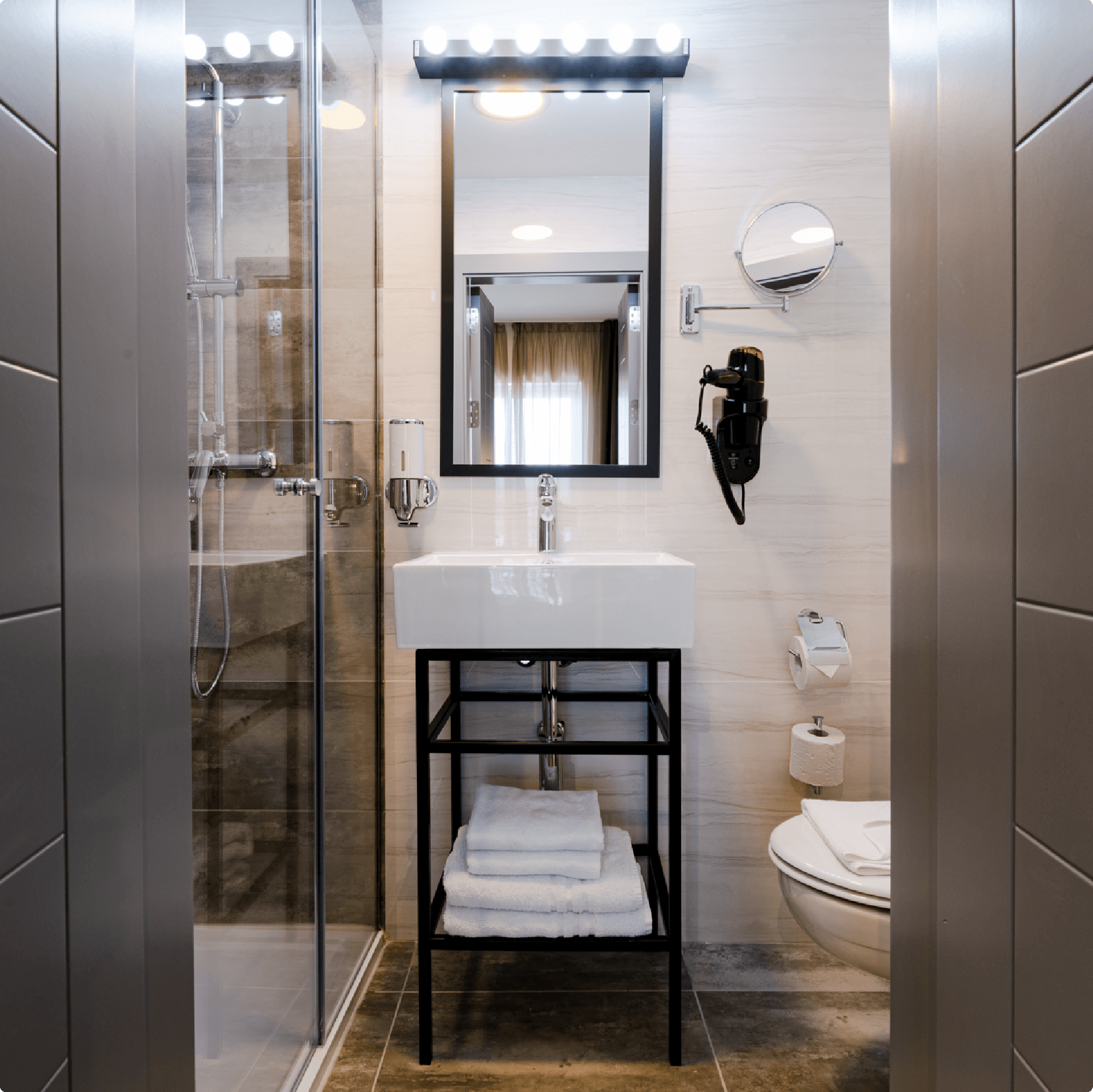 bathroom and its equipment such as mirror, towels, and toilet paper at St hotel room in Malta