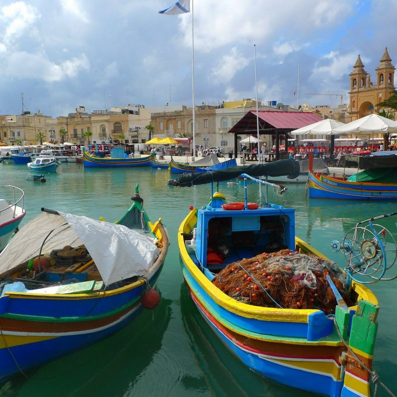 an image of Malta fishing village with some colorful boats and fishing equipment